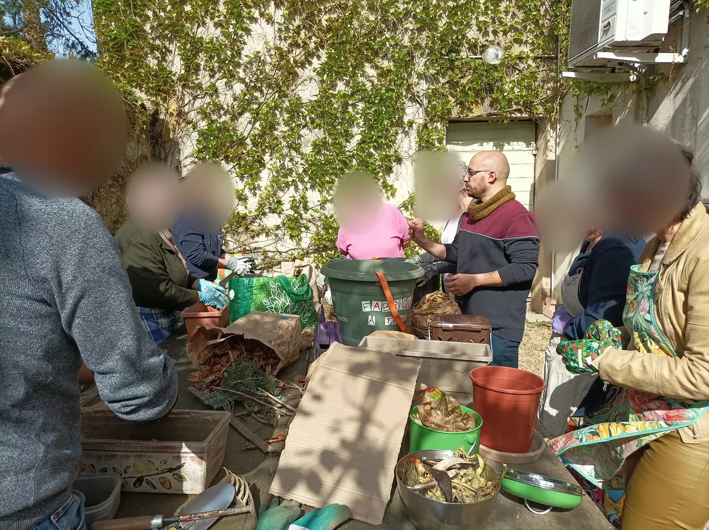 Fabrice anime l'atelier compost autour d'une table avec les participants, dont les visages sont floutés